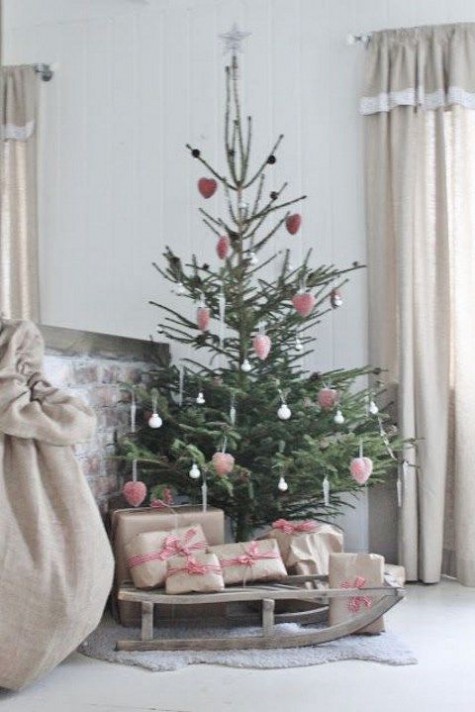 pink ornaments and a sleigh as a tree stand
