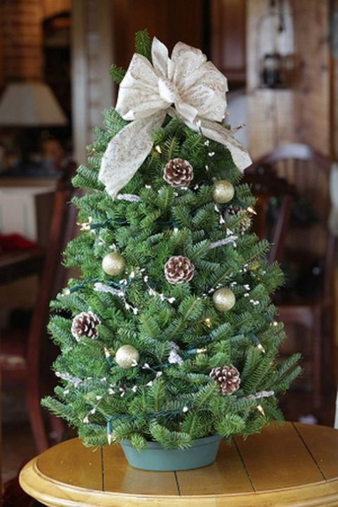 tiny tabletop tree with ornaments, pinecones and a bow