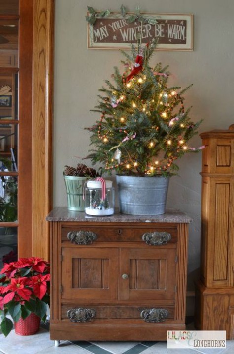 tree in a tin bucket with berries and lights