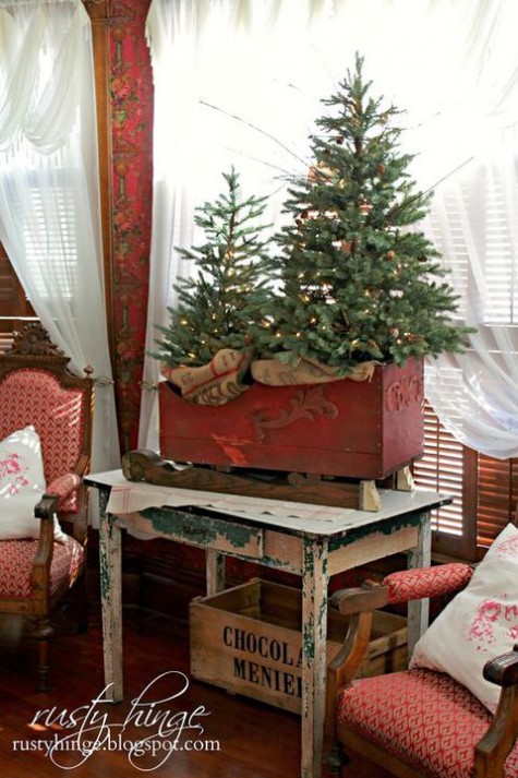 two small tree in a vintage sleigh decorated with lights