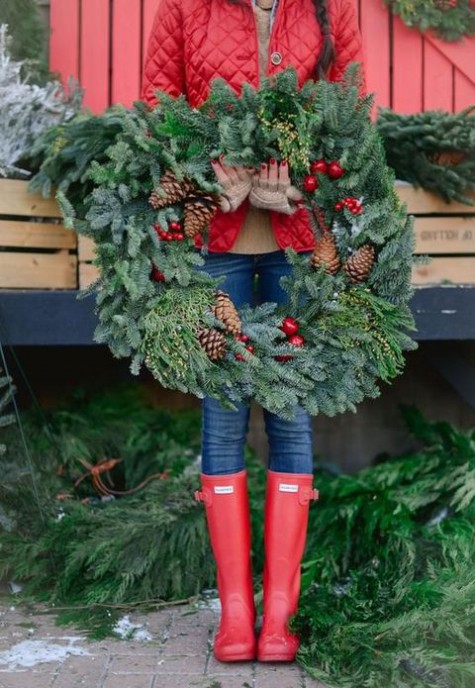 an evergreen wreath with pinecones and red apples