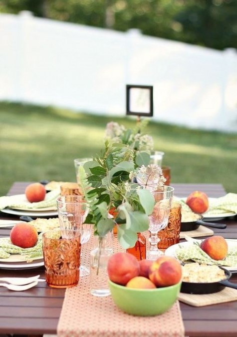 a peachy table runner, green napkins and greenery and fresh peach centerpieces