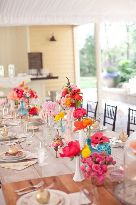 colorful flowers in red, orange, yellow, fuchsia and pink make up the whole table setting