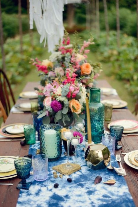 indigo-dyed table runner, green glasses,colorful blooms and candles