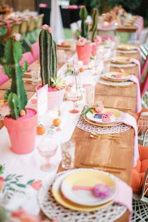 potted cacti, a floral table runner and fruits, bold plates for decor