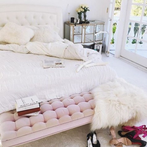 a chic glam space with a creamy diamond upholstery headboard, a pink upholstered bench and a mirror dresser