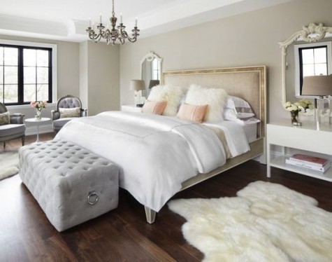 a grey velvet ottoman and chairs, a refined chandelier, a faux fur rug and pillows, two peachy pillows