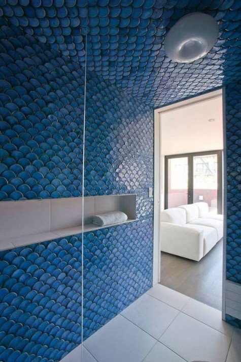 a shower space completely covered with blue fishscale tiles