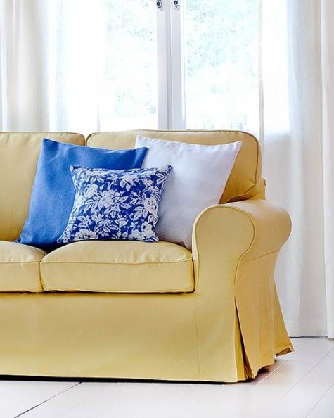 a sleek yellow Ektorp cover accessorized with blue and white pillows