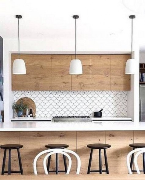 a white and light-colored kitchen is accentuated with a white fishscale tile backsplash