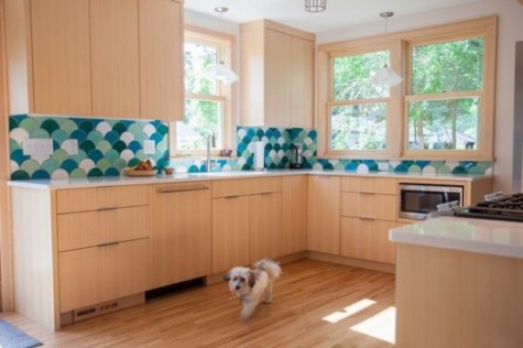 light-colored wood kitchen with green, aqua and white tile backsplash