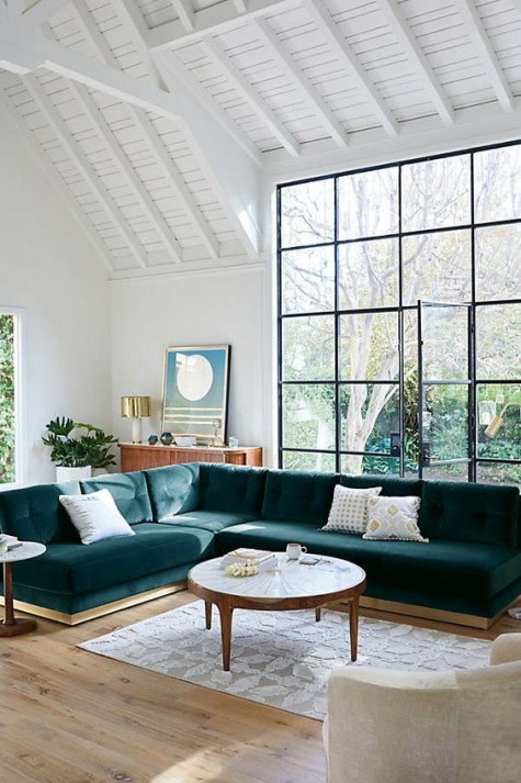a largesectional dark green velvet sofa is a centerpiece of this room