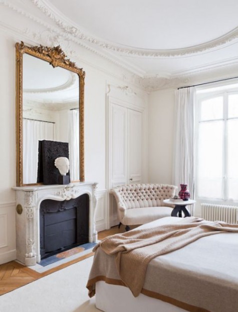 a neutral bedroom made more refined and chic with a large vintage mirror over the fireplace
