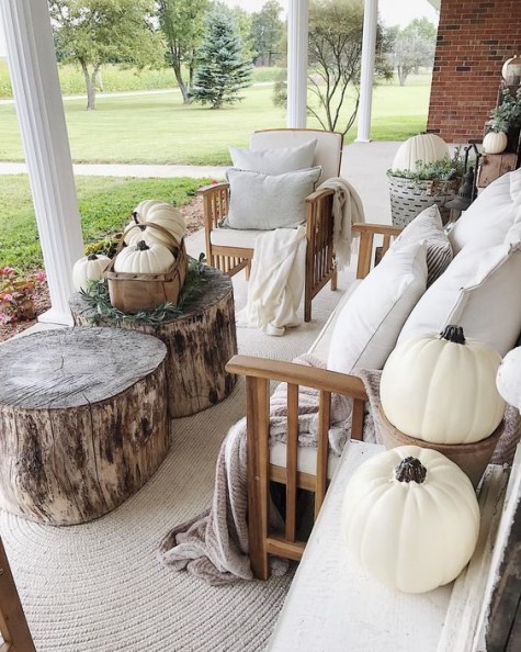 a chic neutral porch with a wooden benchand chair_ neutral textiles and white pumpkins for decor