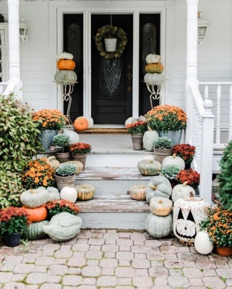 a cozy neutral porch with pumpkins_ orange blooms and pumpkin stands next to the door