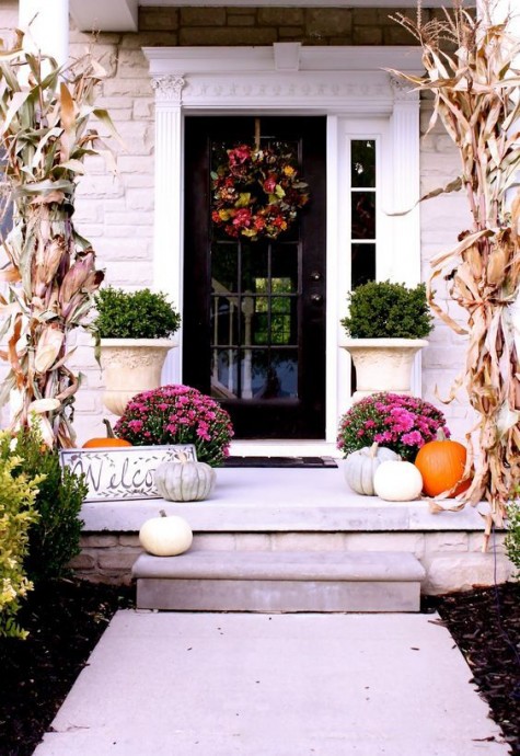 a lively porch with pink flowers_ white and orange pumpkins_ corn husks and boxwood