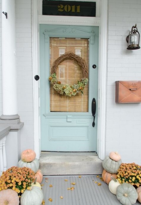 a neutral porch with a wreath_ neutral real pumpkins and fall blooms in baskets