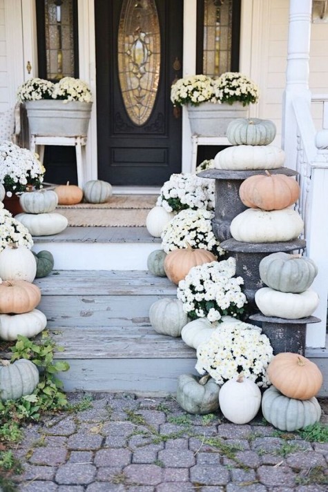 a neutral porch with real pumpkins and white flowers potted into metal bathtubs