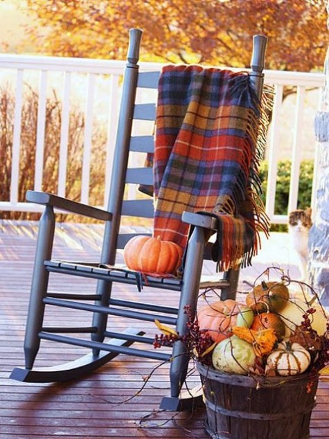 a rocking chair with a plaid blanket and a faux pumpkin display in a wooden basket