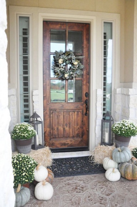 a rustic porch with heirloom pumpkins_ hay_ lanterns and neutral blooms
