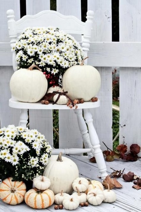 a white chair with white pumpkins and blooms and acorns