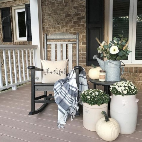 neutral decor with a black chair_ white blooms_ a watering can and a plaid blanket