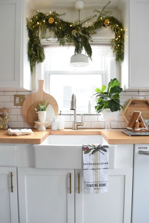 a fir tree garland with lights and citrus over the window