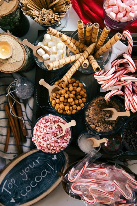 a hot cocoa bar with yummies and a chalkboard wood slice sign