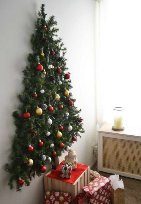 a wall mounted Christmas tree with pine garlands and Christmas ornaments