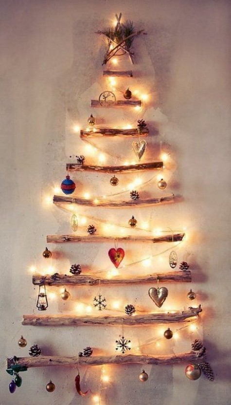 a wall tree of driftwood decorated with lights, ornaments and pinecones