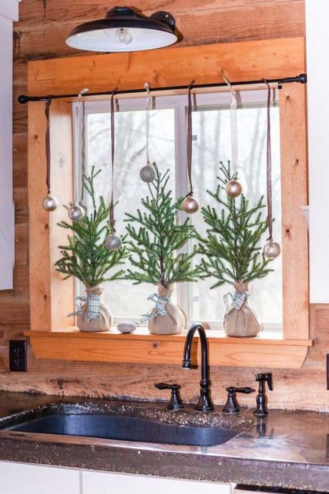 a windowsill with metallic ornaments and small fir trees in burlap