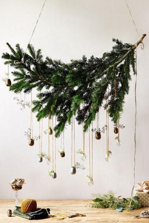 an evergreen branch with tiny vases with greenery hanging from it