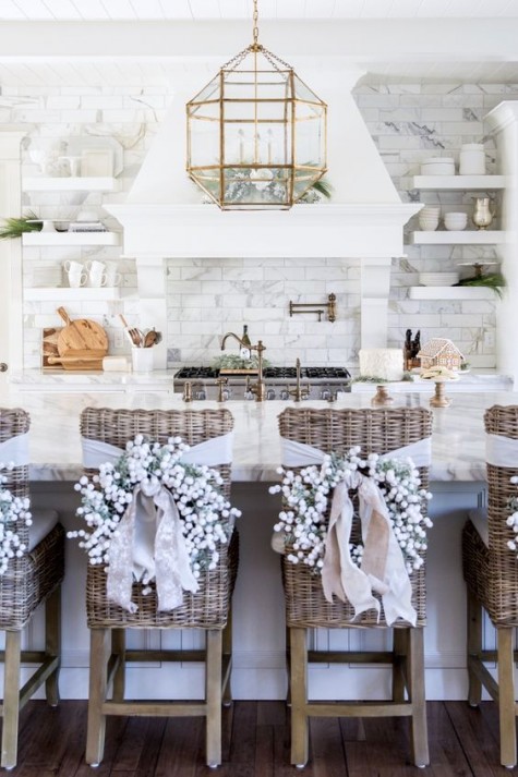 flocked tree wreaths with white ribbons on the kitchen chairs