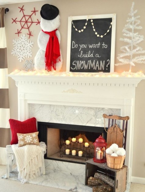 a lit up mantel with a snowman, a chalkboard sign, snowflakes and candles