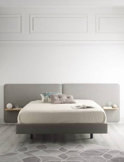 a modern grey upholstered headboard with floating nightstands attached