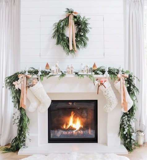 a snowy village scene, an evergreen garland, stockings and a wreath