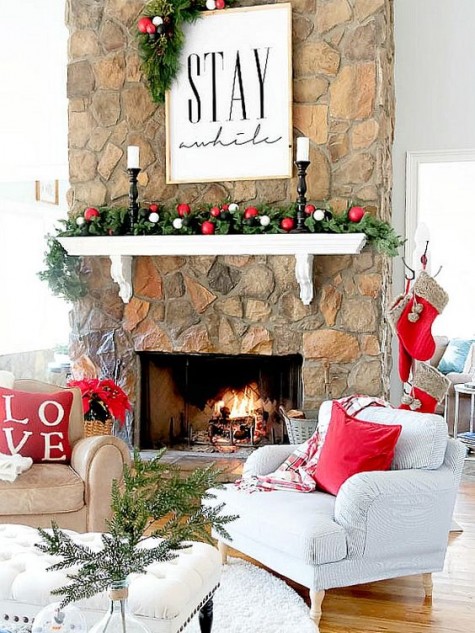 an evergreen garland with white and red ornaments and a framed sign