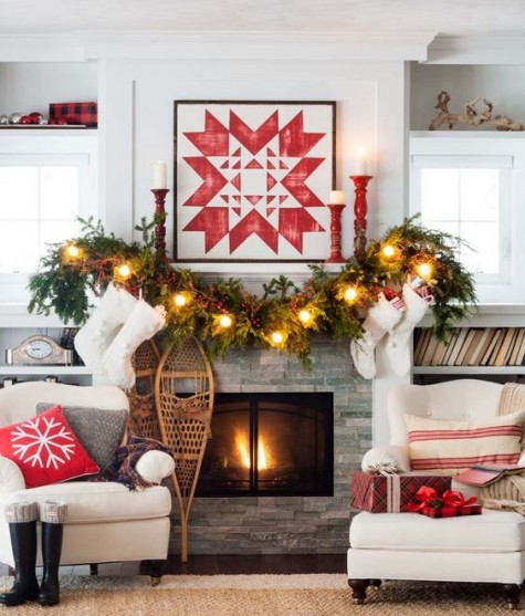 an evergreen lit up garland, a geo snowflake sign and red candle holders