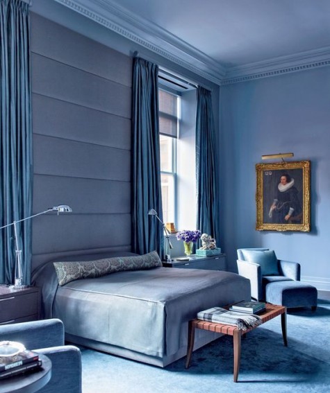an oversized blue upholstered headboard coming up to the ceiling