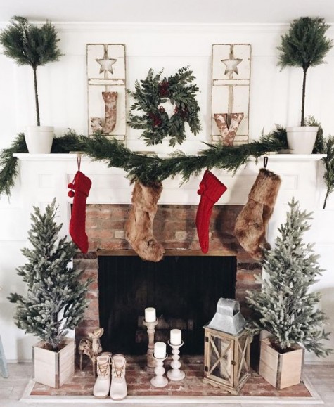 red knit and faux fur stockings, an evergreen garland and wreath, metal letters and Christmas trees