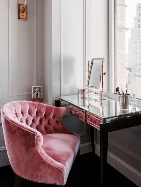 a chic mirrored vanity by the window, a mirror and a pink velvet chair