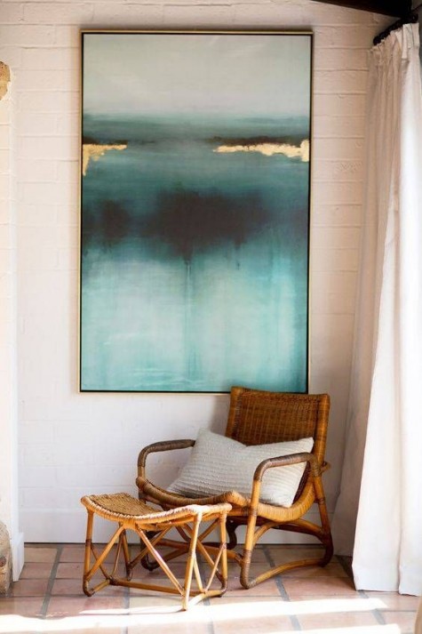 a comfy chair with a footrest and a large artwork