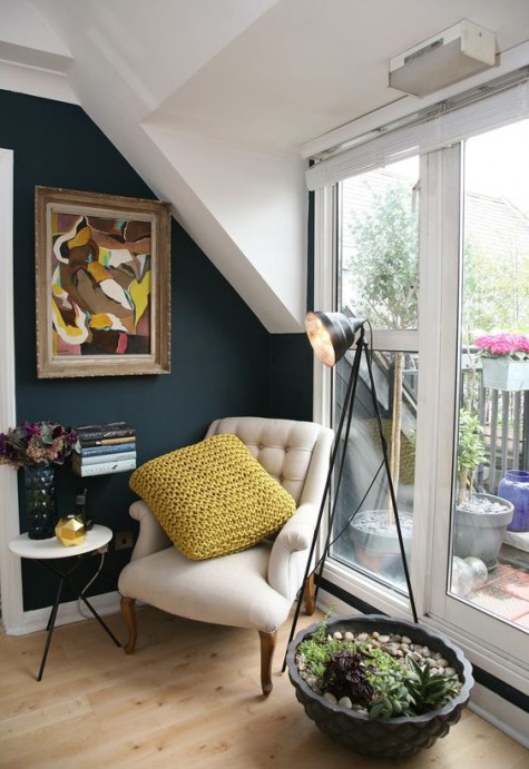 a comfy nook with an armchair, a lamp and some art