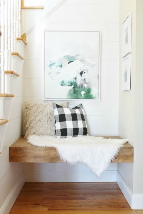 a cozy sitting nook with a thick seat and some artworks