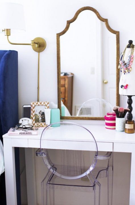 a cute makeup nook with a white vanity, a refined vintage mirror and a sconce