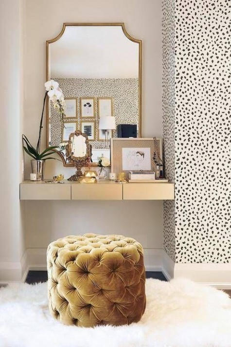 a small makeup nook with a floating vanity, a mirror and na upholstered ottoman