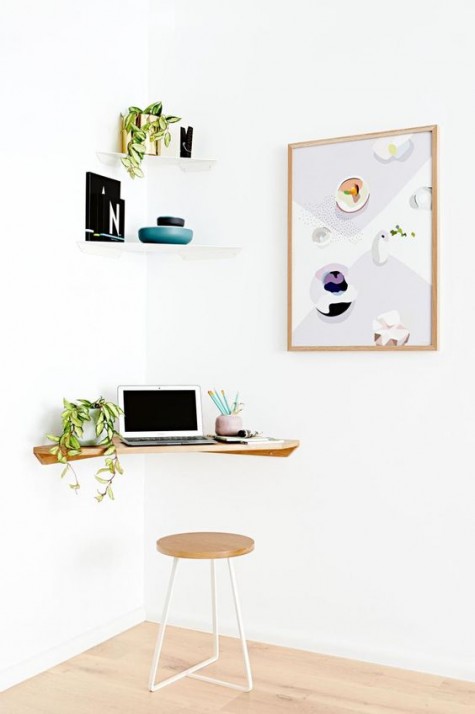 a tiny comfy workspace with a wall-mounted desk, a stool and some shelves
