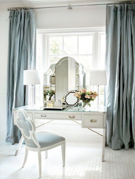 a white art deco vanity, a powder blue chair and a couple of lamps and mirrors for a cool beauty space