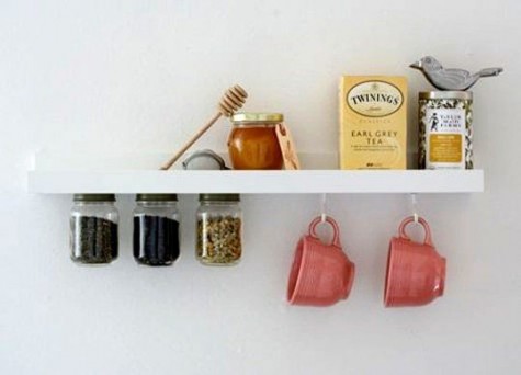a ledge shelf with spicaes, mugs and other stuff on it