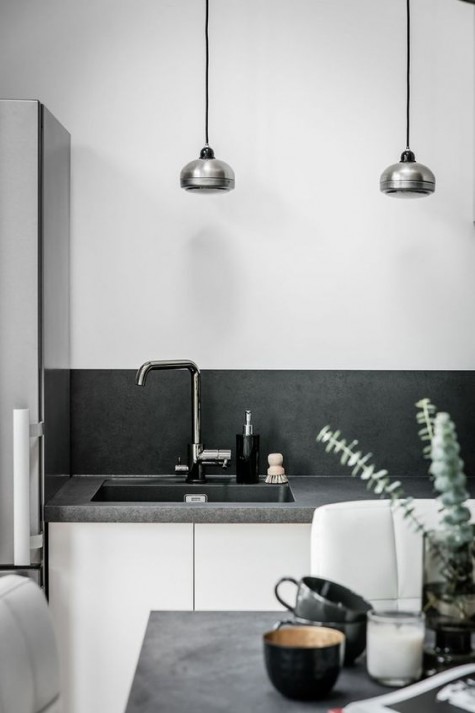 a Scandinavian space with a concrete countertop and backsplash that spruce up usual white cabinets